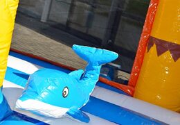 Order a large Indoor beach bounce house with a slide on the jumping surface, climbing tower and fun obstacles beach-themed prints for kids. Buy bounce houses online at JB Inflatables America 